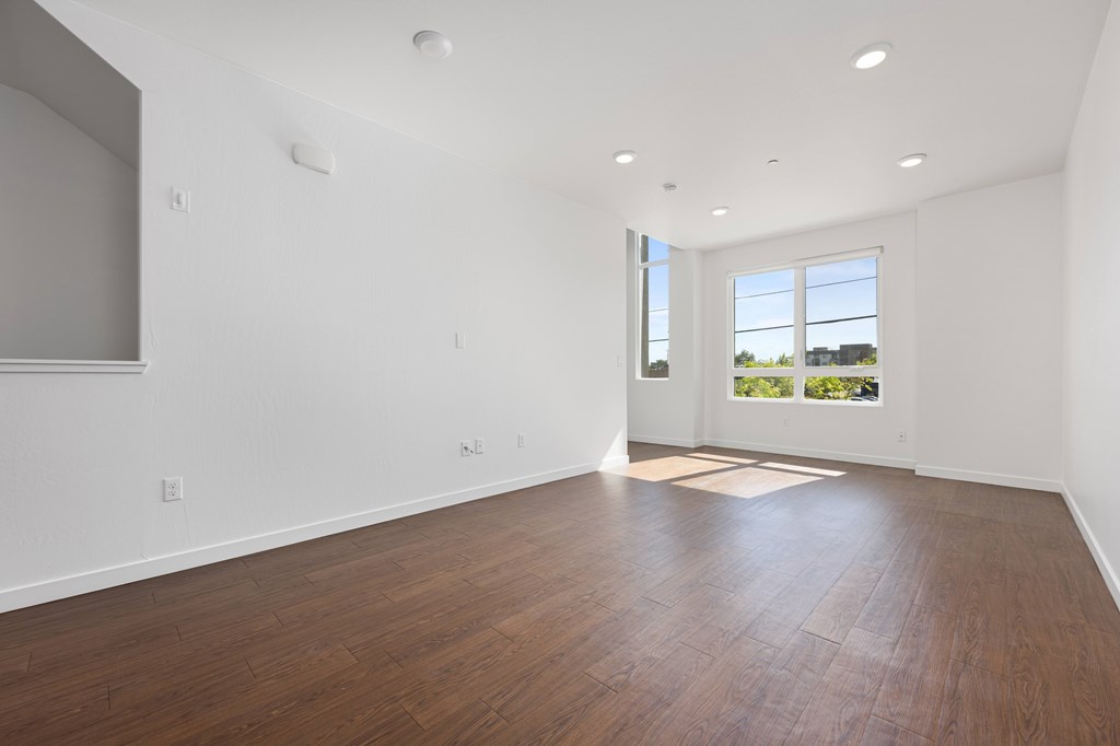 A large empty room with wooden floors and a window.